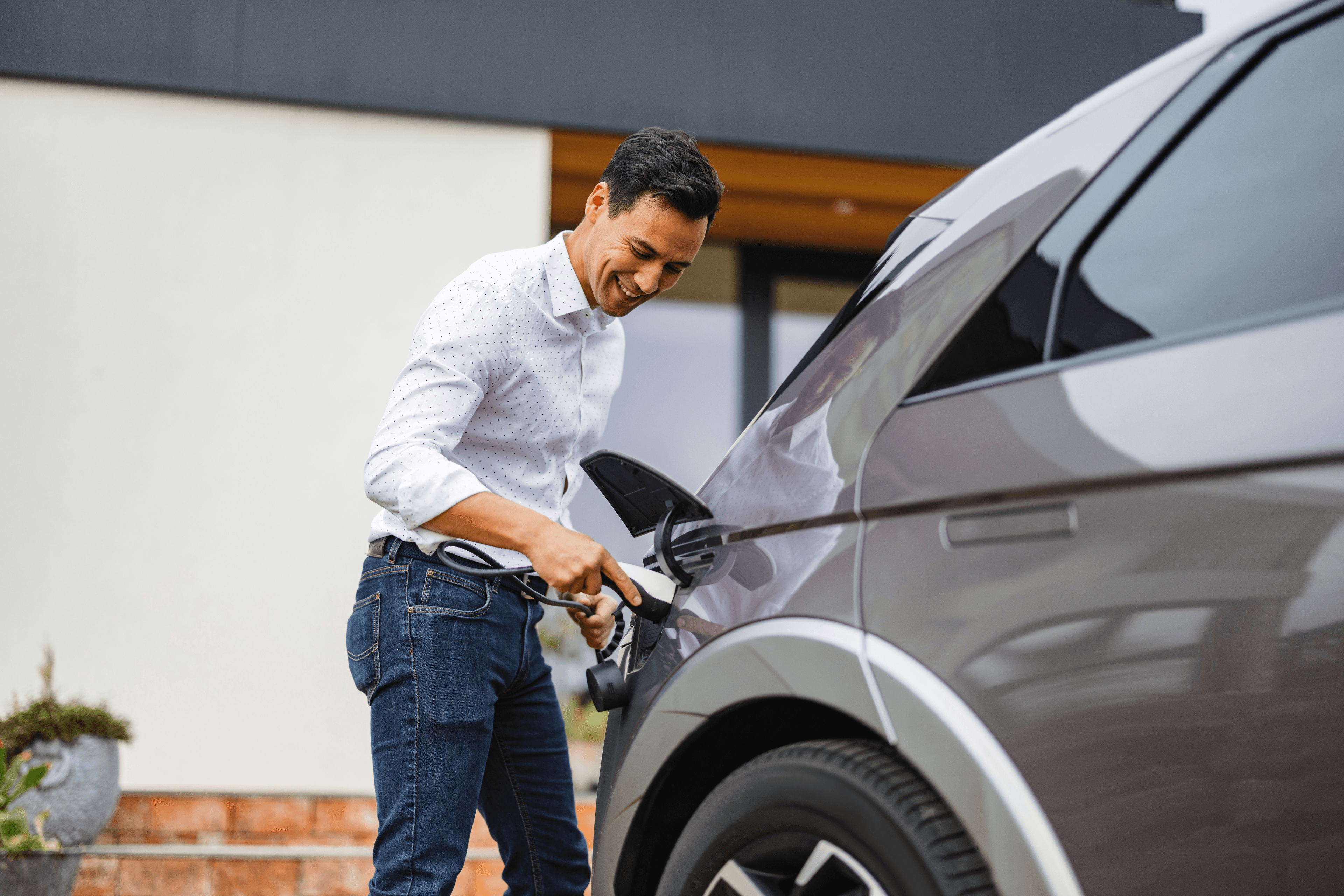 Person plugging in an electric vehicle charger into a car